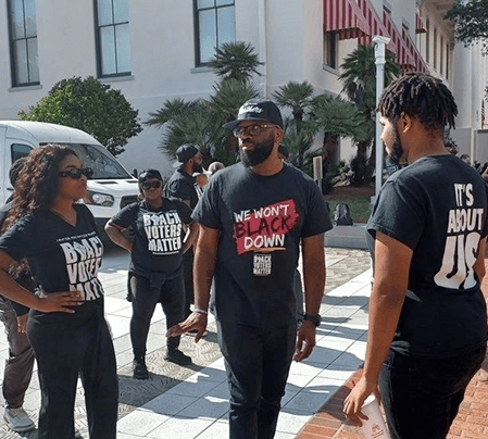 A group of people standing on the sidewalk.