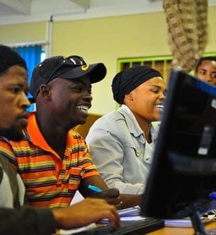 A group of people sitting at a computer.